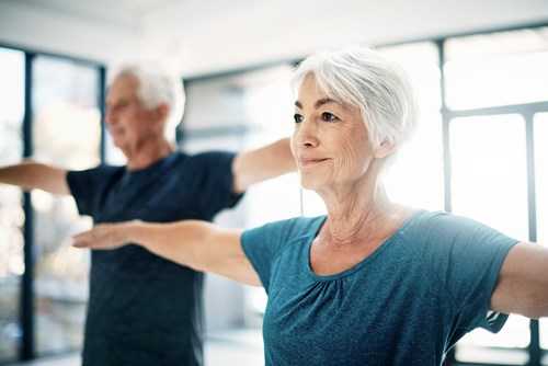 Ett äldre, lyckligt par utövar yoga.